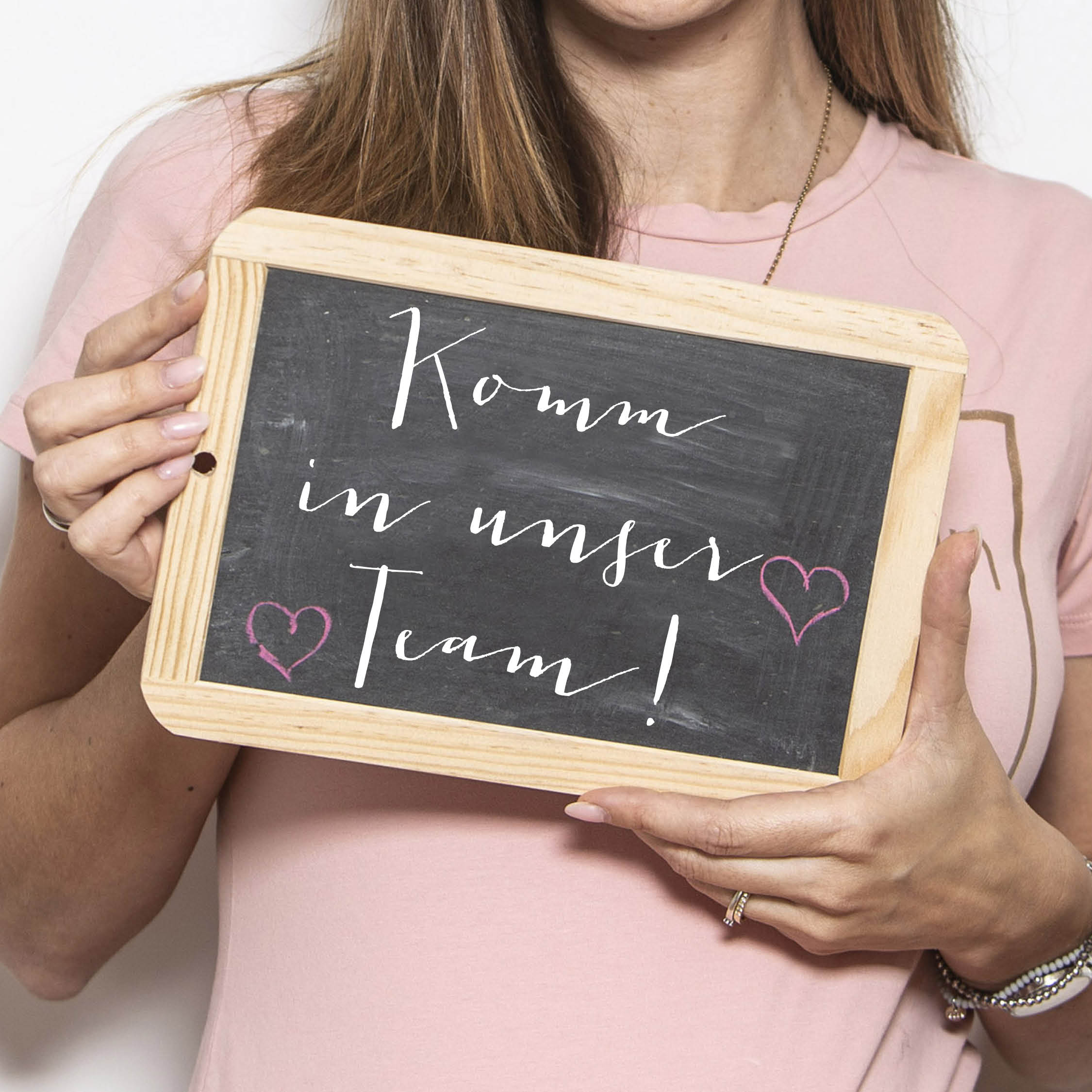 Anzeigenmotiv Frau mit Tafel und Botschaft Komm in unser Team als Aufruf zur ein Stellenangebot für eine Hebamme